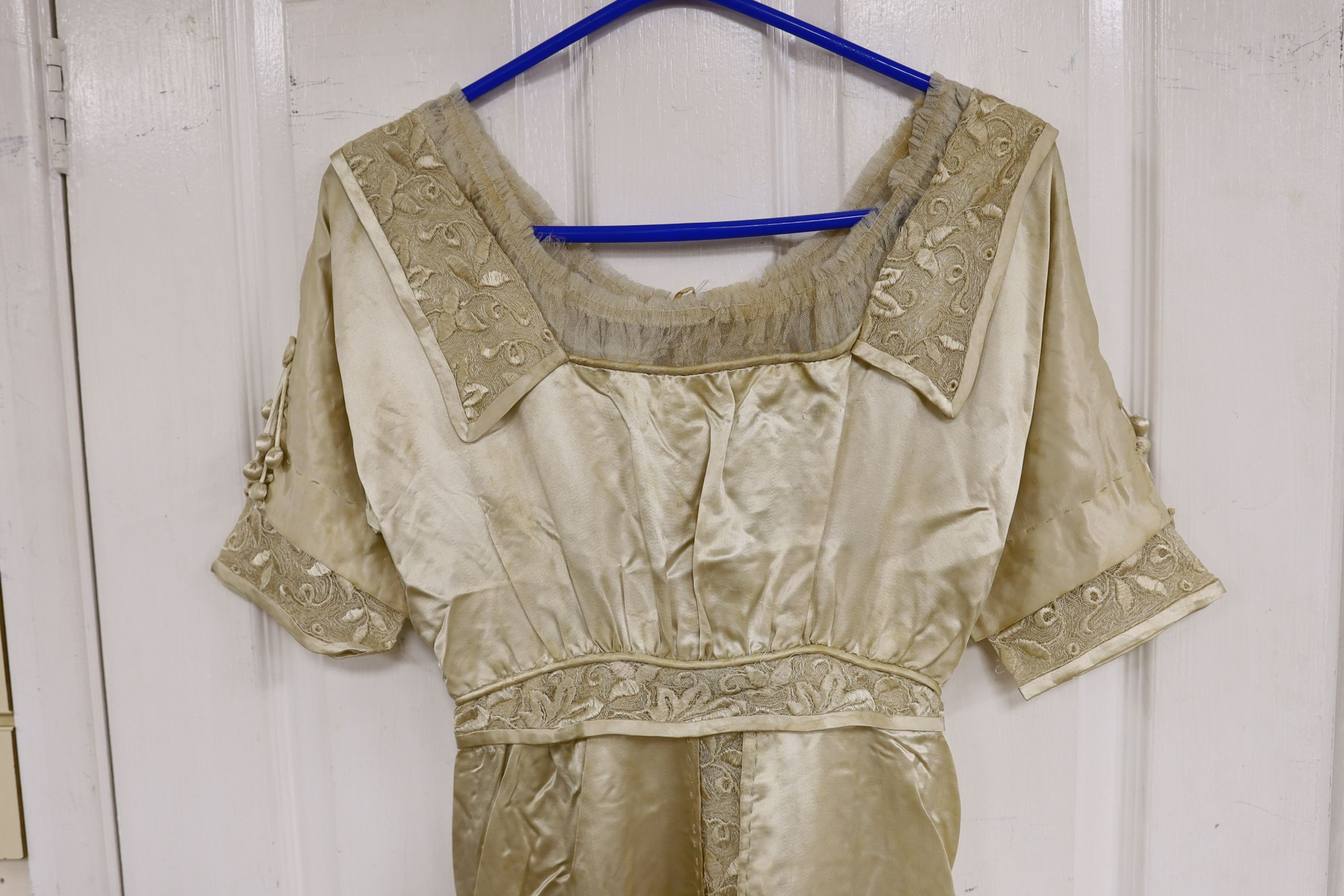 An Edwardian cream satin lady's dress with embroidered panels to base,sleeves front and collar